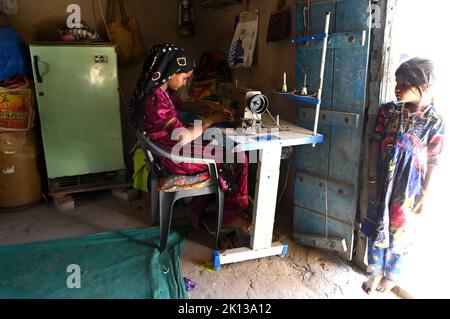 Zwei Stammes-Dorf-Mädchen, eine, die traditionelle Quilt mit Nähmaschine im Dorfhaus, Kachchh Wüstengebiet, Gujarat, Indien, Asien Stockfoto