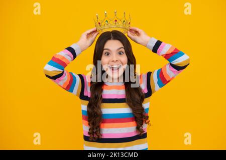 Ein erstaunlicher Teenager. Kleine Königin mit goldener Krone. Teenager-Mädchen Prinzessin hält Krone Tiara. Abschlussball Party, Kinderkonzept. Aufgeregt teen Mädchen. Stockfoto