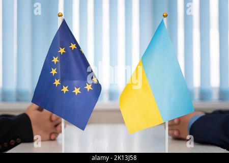 Politische Flaggen der Ukraine und der Europäischen Union. Konzept der Verhandlungen, Zusammenarbeit und Zusammenarbeit der Länder. Vereinbarung zwischen den Regierungen Stockfoto