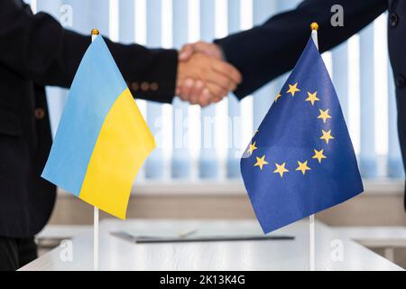 Politische Flaggen der Ukraine und der Europäischen Union. Konzept der Verhandlungen, Zusammenarbeit und Zusammenarbeit der Länder. Vereinbarung zwischen den Regierungen Stockfoto