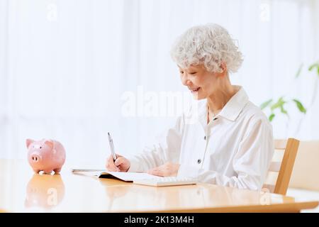 Japanische ältere Frau, die zu Hause Buchhaltung macht Stockfoto