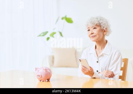 Japanische ältere Frau, die zu Hause Buchhaltung macht Stockfoto