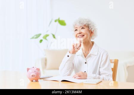 Japanische ältere Frau, die zu Hause Buchhaltung macht Stockfoto