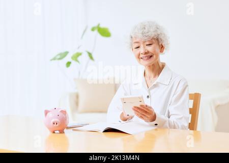 Japanische ältere Frau, die zu Hause Buchhaltung macht Stockfoto