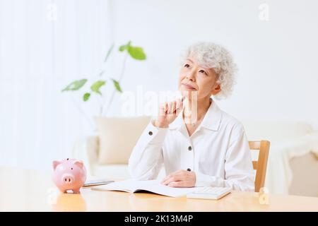 Japanische ältere Frau, die zu Hause Buchhaltung macht Stockfoto