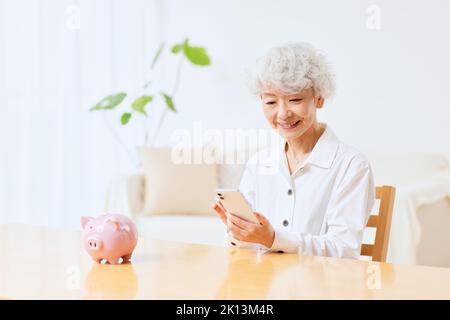 Japanische ältere Frau, die zu Hause Buchhaltung macht Stockfoto