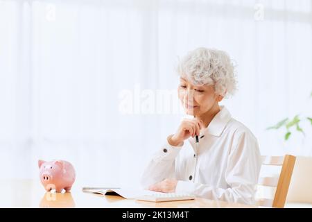 Japanische ältere Frau, die zu Hause Buchhaltung macht Stockfoto