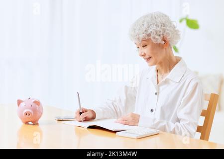 Japanische ältere Frau, die zu Hause Buchhaltung macht Stockfoto