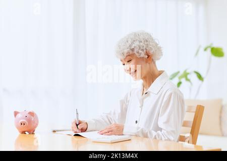Japanische ältere Frau, die zu Hause Buchhaltung macht Stockfoto