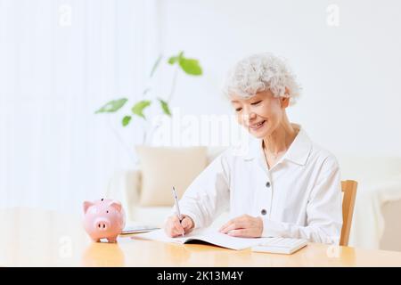 Japanische ältere Frau, die zu Hause Buchhaltung macht Stockfoto