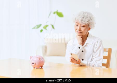 Japanische ältere Frau, die zu Hause Buchhaltung macht Stockfoto