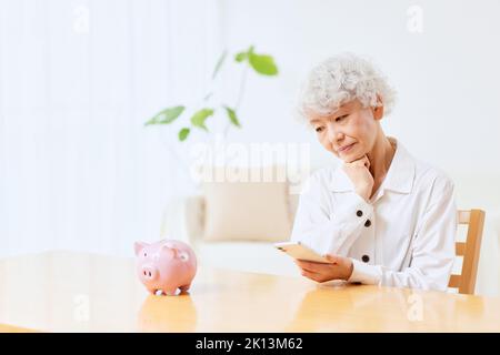 Japanische ältere Frau, die zu Hause Buchhaltung macht Stockfoto