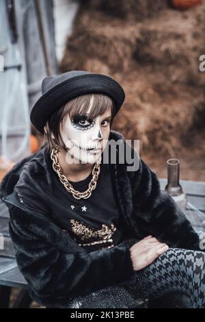 Schöne gruselige kleine Mädchen feiern halloween. Erschreckend schwarz, weiß Halbgesicht Make-up und Hexen-Kostüm, stilvolles Bild. Horror, Spaß bei Kindern Stockfoto