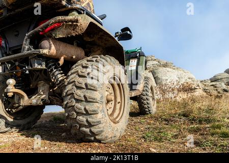 Nahaufnahme Detail untere POV-Ansicht 4x4 awd ATV Fahrzeug auf Schotterpiste unbefestigte Straße im Herbst auf nebligen Berggipfel. Offroad Auto Berg Safari Abenteuer Stockfoto