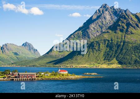 Blick auf den Austnesfjorden mit der Sildpollnes Kirche gegen zerklüftete Berge, Lofoten, Norwegen Stockfoto