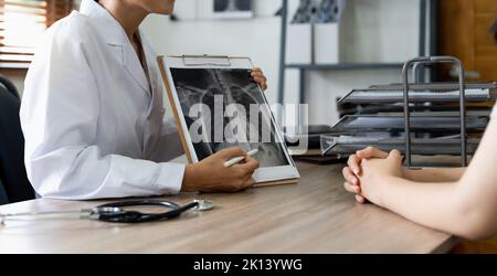 Arzt, der dem Patienten in der Klinik das Röntgenergebnis zeigt Stockfoto