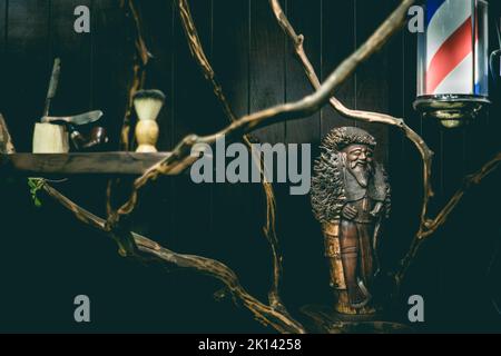 Barber Shop Licht, Holzstatuette, Rasiermesser, Pinsel und antike Pfeife auf einem Barber Shop Regal Stockfoto