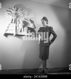 Damenmode im Jahr 1940s. Eine junge Frau, die für ein Damenmagazin fotografiert wurde, um die Damenmode von 1945 zu zeigen. Das weibliche Modell trägt eine passende Jacke und einen passenden Rock zusammen mit einem Hut und Handschuhen. Schweden 1945. Kristoffersson Ref. R2-5 Stockfoto