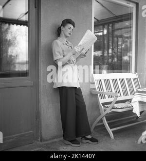 Damenmode im Jahr 1940s. Eine junge Frau, die für ein Damenmagazin fotografiert wurde, um die Damenmode von 1945 zu zeigen. Das weibliche Modell trägt eine breite Hose und einen kurzen Mantel oder eine Jacke. Schweden 1945. Kristoffersson Ref. R5-2 Stockfoto