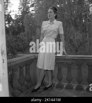 Damenmode im Jahr 1940s. Eine junge Frau, die für ein Damenmagazin fotografiert wurde, um die Damenmode von 1945 zu zeigen. Das weibliche Modell trägt ein Kleid mit einem Gürtel, der mit Taschen und Knöpfen verziert ist. Schweden 1945. Kristoffersson Ref. R6-3 Stockfoto