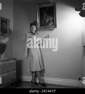 Damenmode im Jahr 1940s. Eine junge Frau, die für ein Damenmagazin fotografiert wurde, um die Damenmode von 1945 zu zeigen. Das weibliche Modell trägt ein kariertes gemustertes Kleid Sweden 1945. Kristoffersson Ref. R6-5 Stockfoto