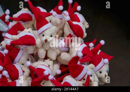 Auf einem Markt in York, North Yorkshire, England, werden süße kleine weiße Teddybären mit rot-weißen Weihnachtshüten ausgestellt. Stockfoto