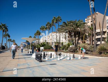 Ein Schachspiel an der Küste von Estepona an der Costa del Sol in Südspanien. Neben dem Playa de la verläuft eine von Palmen gesäumte Promenade, der Paseo Marítimo Stockfoto