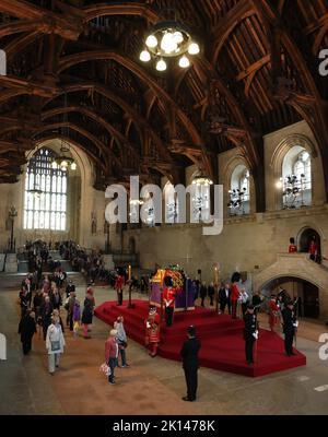 Die Leute legen sich am Sarg Ihrer Majestät Königin Elizabeth II. Vorbei, die vier Tage lang in der Westminster Hall liegt. Der Sarg ist mit dem königlichen Standard drapiert, auf dem die Staatsinstrumente, die imperiale Staatskrone, die Kugel und das Zepter liegen. Eine kontinuierliche Mahnwache wird am Donnerstag von den Leibwächtern des königlichen Korps des ehrenwerten Gentleman at Arms, der königlichen Gesellschaft der Bogenschützen, den Yeomen der Garde, unterstützt von den Yeomen Wardern des Tower of London und von Offizieren der Haushaltsabteilung in London gehalten. 15. September 2022. Das Begräbnis von Königin Elizabeth II. Wird in stattfinden Stockfoto