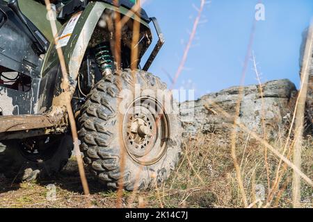 Nahaufnahme Detail untere POV-Ansicht 4x4 awd ATV Fahrzeug auf Schotterpiste unbefestigte Straße im Herbst auf nebligen Berggipfel. Offroad Auto Berg Safari Abenteuer Stockfoto