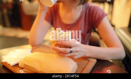 Nahaufnahme einer hungrigen Frau in Gläsern ist der Verzehr eines köstlichen Hühnershawarmas. Stockfoto