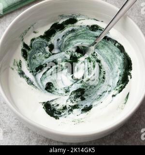 Schüssel Joghurt mit gesundem grünen Spirulina-Pulver aus nächster Nähe zum Frühstück Stockfoto