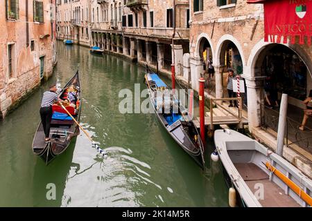 Touristen, die mit Gondeln, typischen Booten, in der Stadt Venedig, Italien, reisen Stockfoto