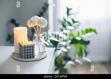 Home Duft Duft Diffusor und brennende Kerzen auf dem Tisch. Innenraumelemente. Speicherplatz kopieren Stockfoto