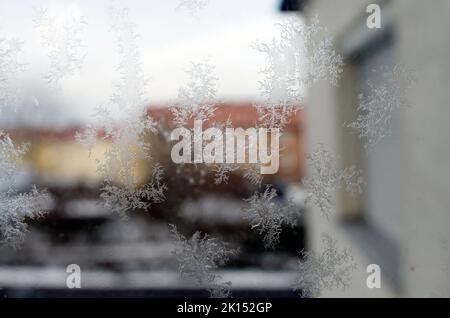 Gefrorene Eiskristalle auf einem Stadtfenster im eisigen Londoner Winter bilden kristalline Formen mit verschwommenen Gebäuden im Hintergrund Stockfoto