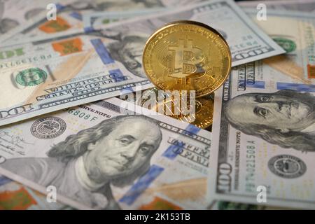 Goldene Bitcoin-dollar auf Hintergrund und Spiegelreflexion. Porträt von Benjamin Franklin aus amerikanischen Dollar. Bitcoin BTC virtuelles Geld Stockfoto