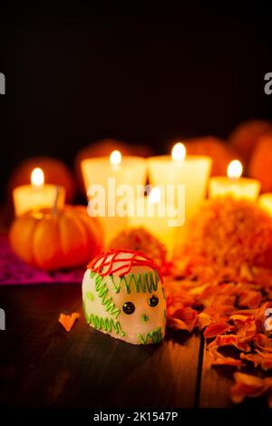 Zuckerschädel mit Kerze, Crepasuchil-Blüten oder Ringelblume und Papel Picado. Dekoration traditionell in Altären für die Feier des Tages verwendet Stockfoto