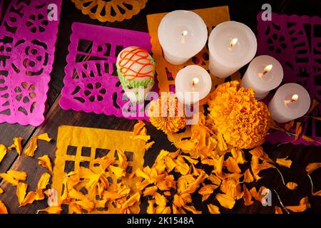 Zuckerschädel mit Kerze, Crepasuchil-Blüten oder Ringelblume und Papel Picado. Dekoration traditionell in Altären für die Feier des Tages verwendet Stockfoto