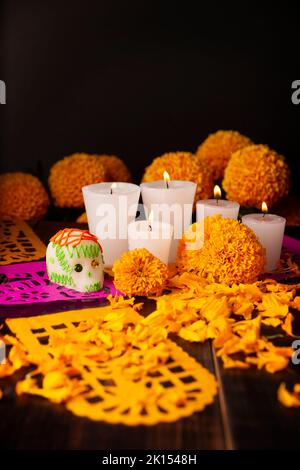Zuckerschädel mit Kerze, Crepasuchil-Blüten oder Ringelblume und Papel Picado. Dekoration traditionell in Altären für die Feier des Tages verwendet Stockfoto