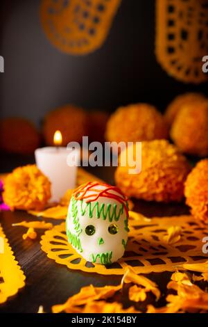 Zuckerschädel mit Kerze, Crepasuchil-Blüten oder Ringelblume und Papel Picado. Dekoration traditionell in Altären für die Feier des Tages verwendet Stockfoto