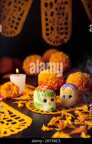 Zuckerschädel mit Kerze, Crepasuchil-Blüten oder Ringelblume und Papel Picado. Dekoration traditionell in Altären für die Feier des Tages verwendet Stockfoto