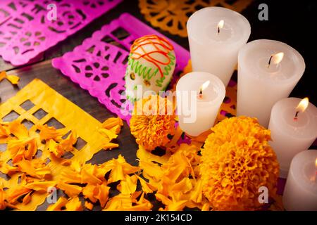 Zuckerschädel mit Kerze, Crepasuchil-Blüten oder Ringelblume und Papel Picado. Dekoration traditionell in Altären für die Feier des Tages verwendet Stockfoto