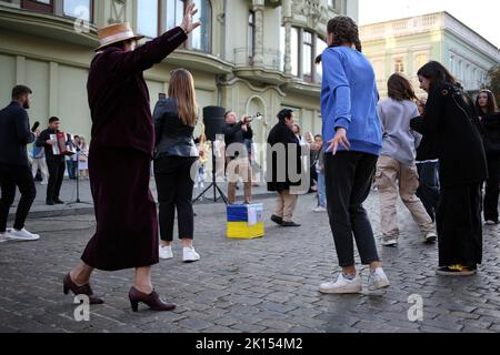 Man sieht, wie die Leute zu einer Straßenmusikkapelle tanzen. Trotz der umfassenden Invasion der Russischen Föderation, an den Wochenenden, Freude und Leben herrschen auf der Hauptstraße von Odessa - Deribasovskaya, Urlauber gehen, tanzen, Spaß haben, wie in Friedenszeiten. Deribasovskaya Straße - eine der zentralen Straßen der Stadt Odessa, ist eine der wichtigsten Sehenswürdigkeiten der Stadt.seit dem Ende des 20.. Jahrhunderts, die meisten von Deribasovskaya wurde für den Verkehr gesperrt und ist eine Fußgängerzone. Deribasowskaja ist ein beliebter Ort für Feste. Es gibt zahlreiche Cafés und Geschäfte auf Deribasovskaya. Die Straße bekam ihren Namen Stockfoto