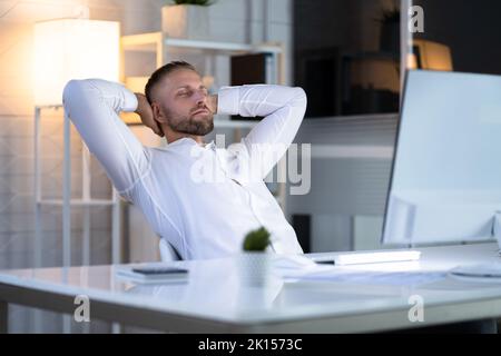 Geschäftsmann, Der In Einem Bürostuhl Sitzt Und Sich In Der Nähe Des Computers Entspannt Stockfoto