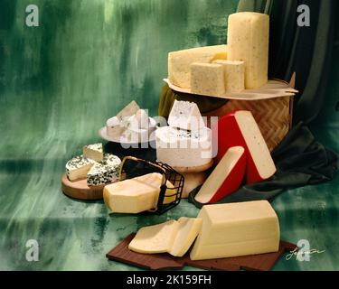 Malerisches Bild dänischer Käsesorten in Gruppenfoto auf grün getöntem, meliertem Hintergrund. Studio-Tischplatte. Klassisches Bild Stockfoto