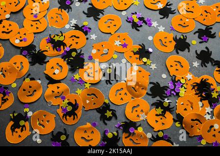 Halloween Hintergrund: Glänzendes Konfetti in Form von orangefarbenen Kürbissen, schwarzen Spinnen und bunten Sternen grün, lila Farbe. Speicherplatz kopieren. Stockfoto