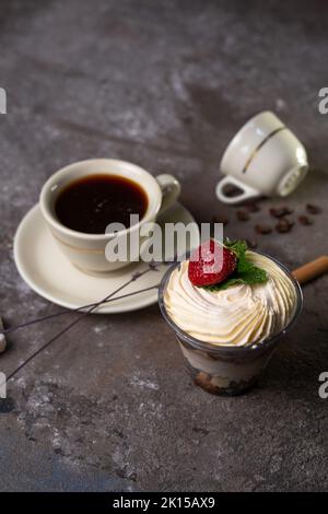 Dessert in einem Glas mit Erdbeeren und einer Tasse Tee. Stockfoto