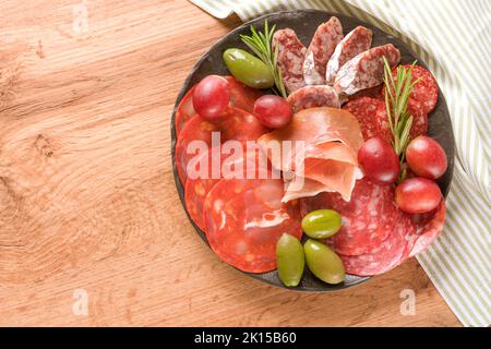 Traditionelle italienische Antipasti. Wurstplatte mit verschiedenen Wurstsorten - Salami, bresaola, proscuitto serviert mit Oliven auf Holztisch. B Stockfoto