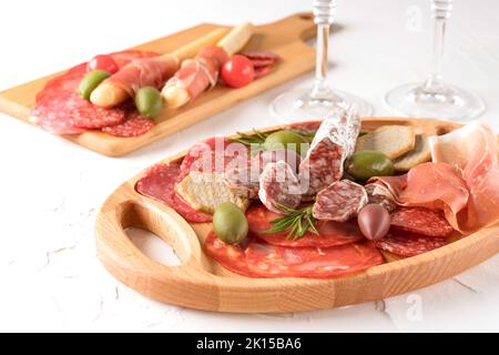 Wurstplatte mit verschiedenen Wurstsorten - Salami, Bresaola, Proscuitto serviert mit Crackern und Oliven. Menühintergrund. Traditionelles italien Stockfoto