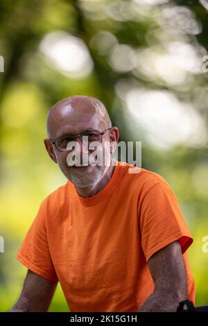 Porträt eines lächelnden älteren Mannes mit Brille in T-Shirt, der sich nach dem Joggen im Wald ausruhte Stockfoto