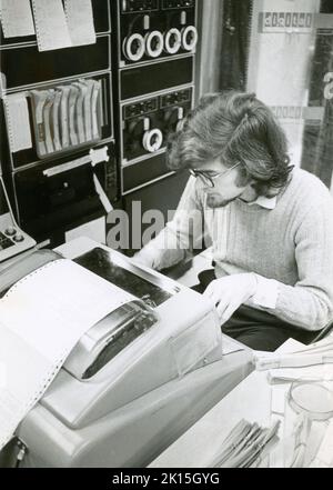 Historisches Bild eines Mannes, der ein frühes Computersystem zur Datenanaylse verwendet. „Soziologe, der einen Computer verwendet, um Daten aus einem Forschungsprojekt zu analysieren.“ Stockfoto